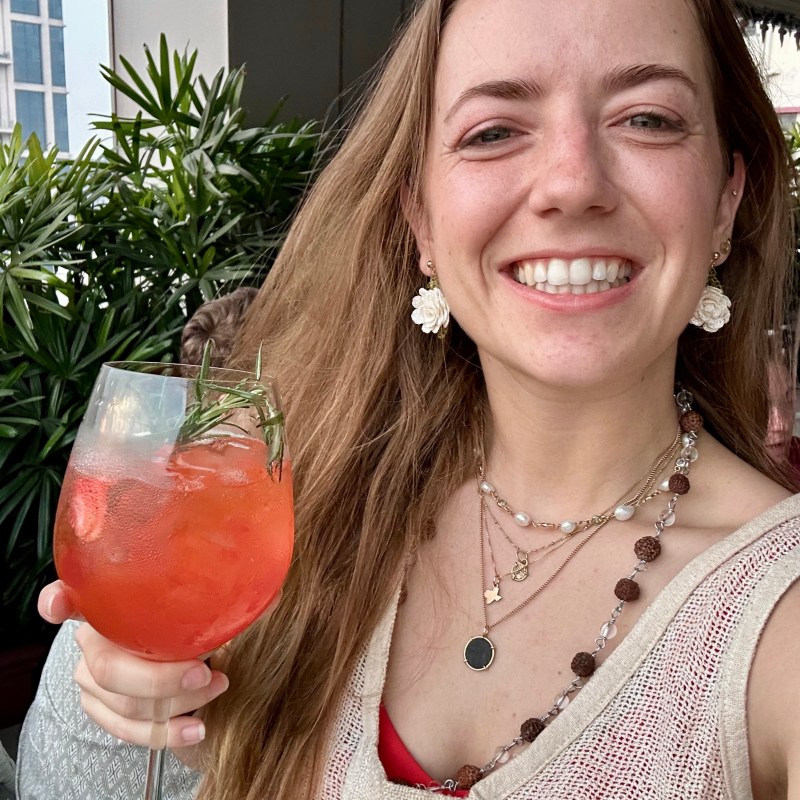 Danielle_S a woman is smiling while holding a glass of wine